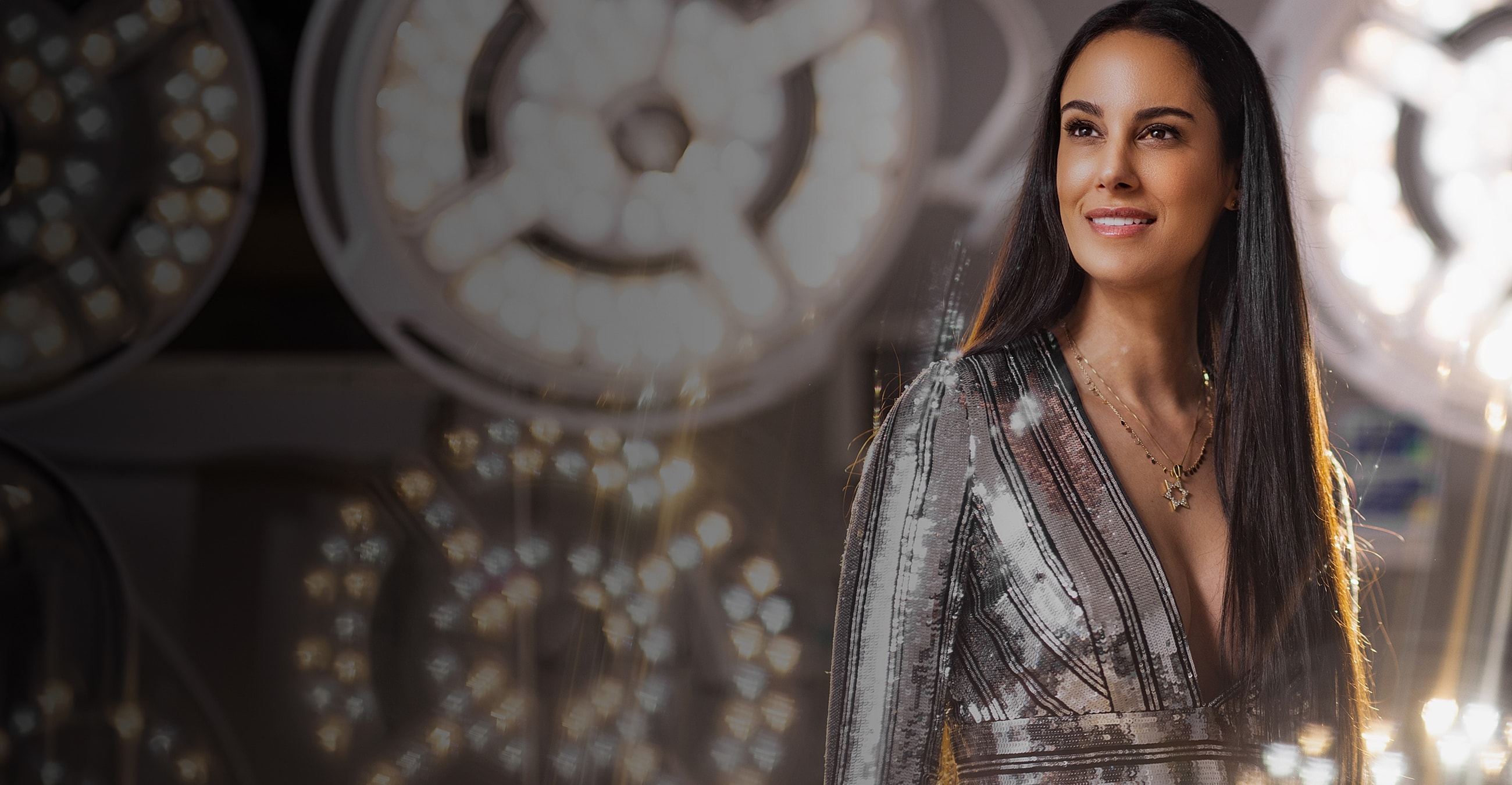 Woman smiling in a sparkly dress with lights.