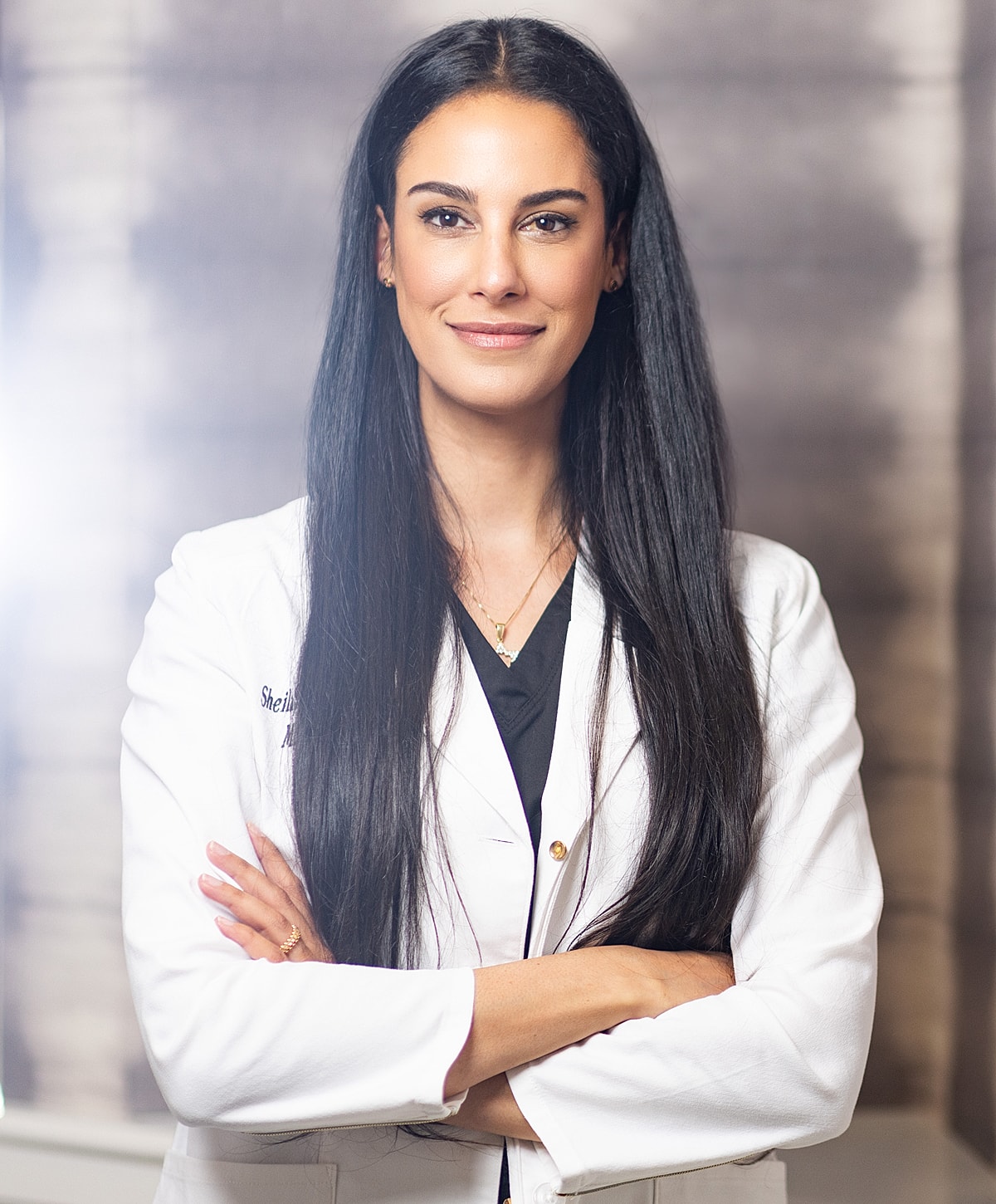 Professional woman in a medical coat, arms crossed.