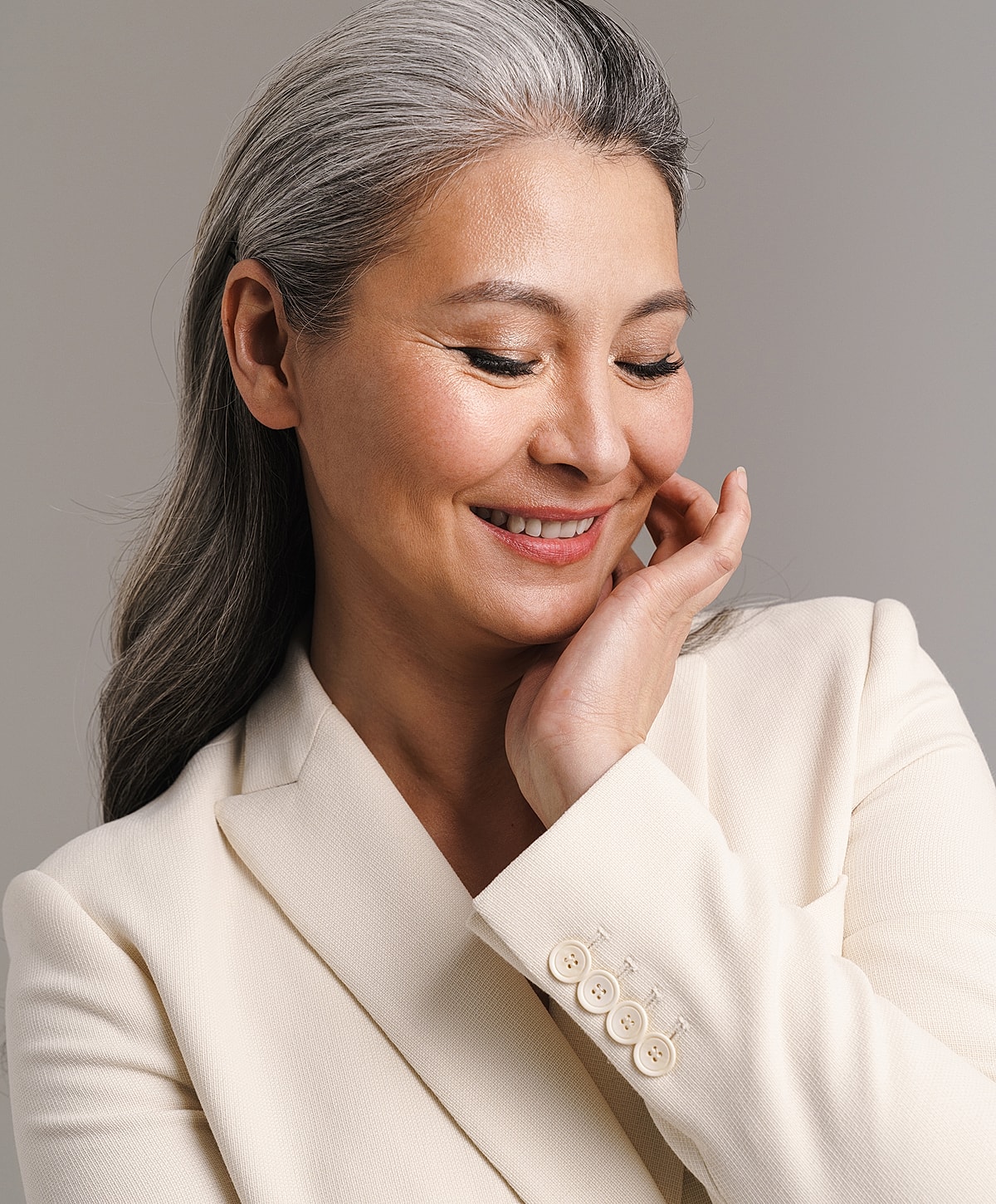 Smiling woman with gray hair in elegant attire.