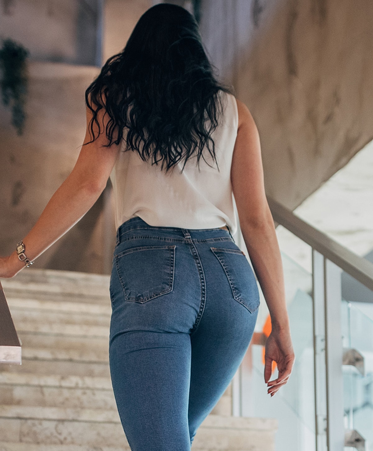 Woman walking up stairs in fitted jeans.
