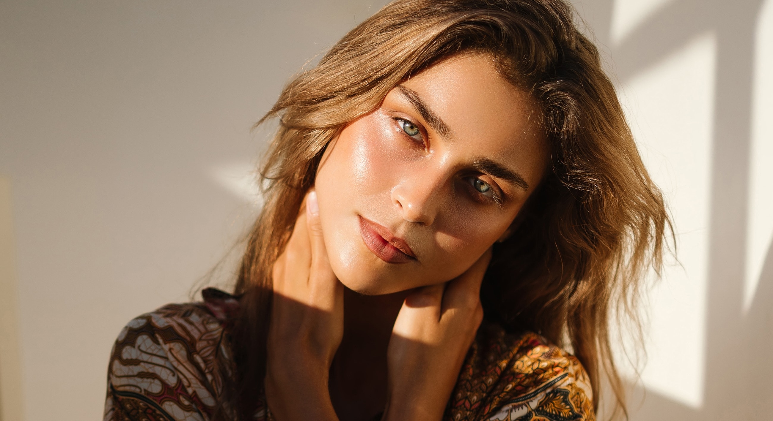 Woman with sunlit face, soft expression, natural beauty.