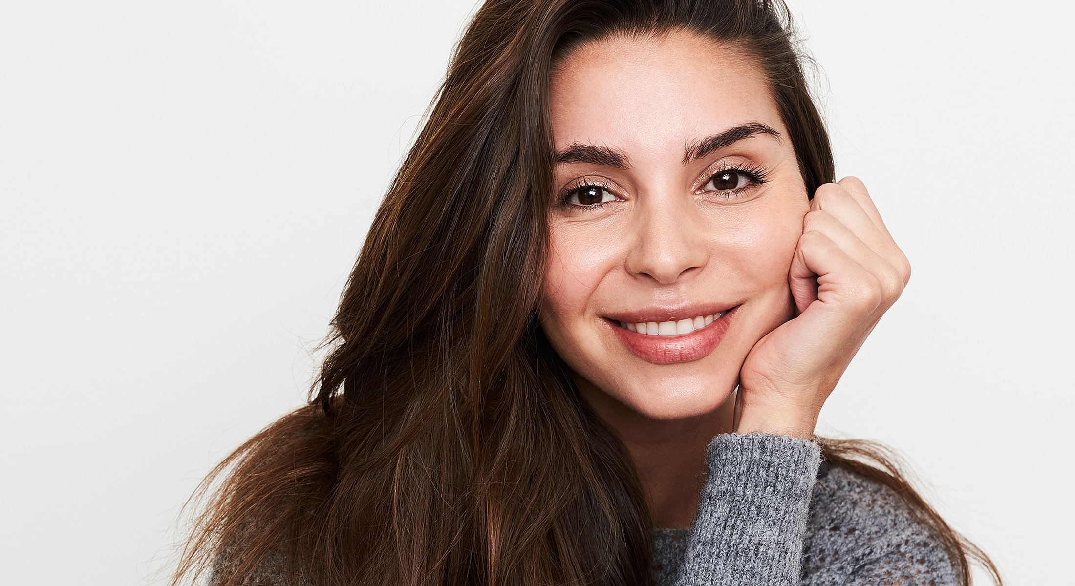 Smiling woman with long hair against white background.