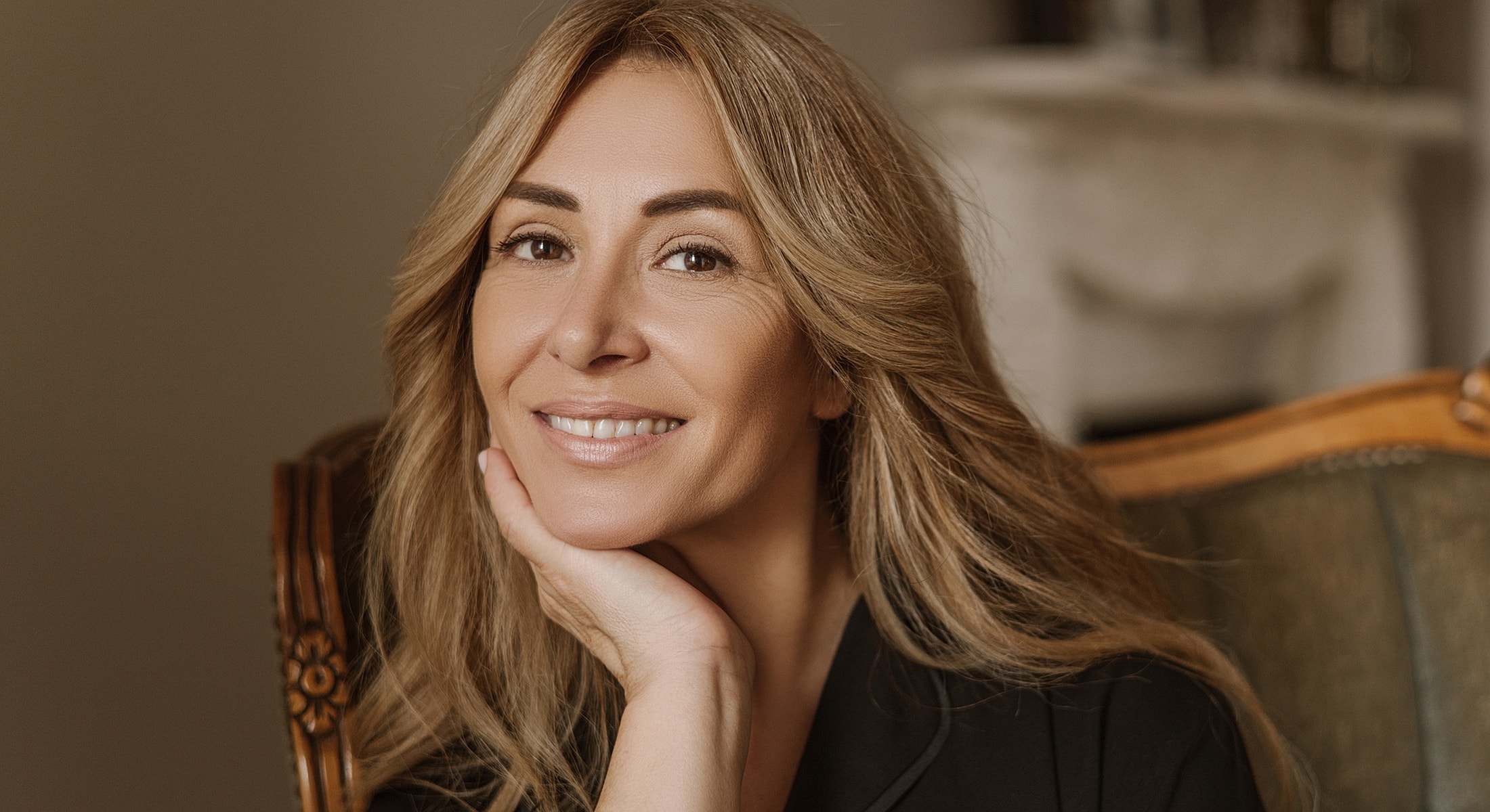 Smiling woman sitting elegantly indoors.